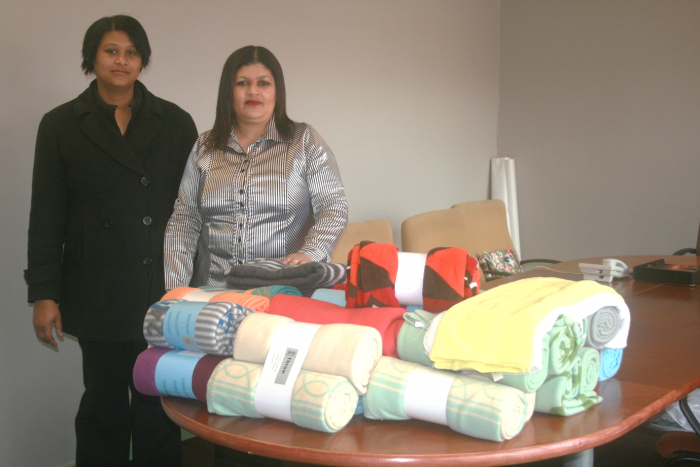 Yolandi George, left, Operations Manager at We Care, and Ashlene Arends, We Care CEO warmed bodies and hearts with blankets donated by AfriCoast engineers in support of Mandela Day.